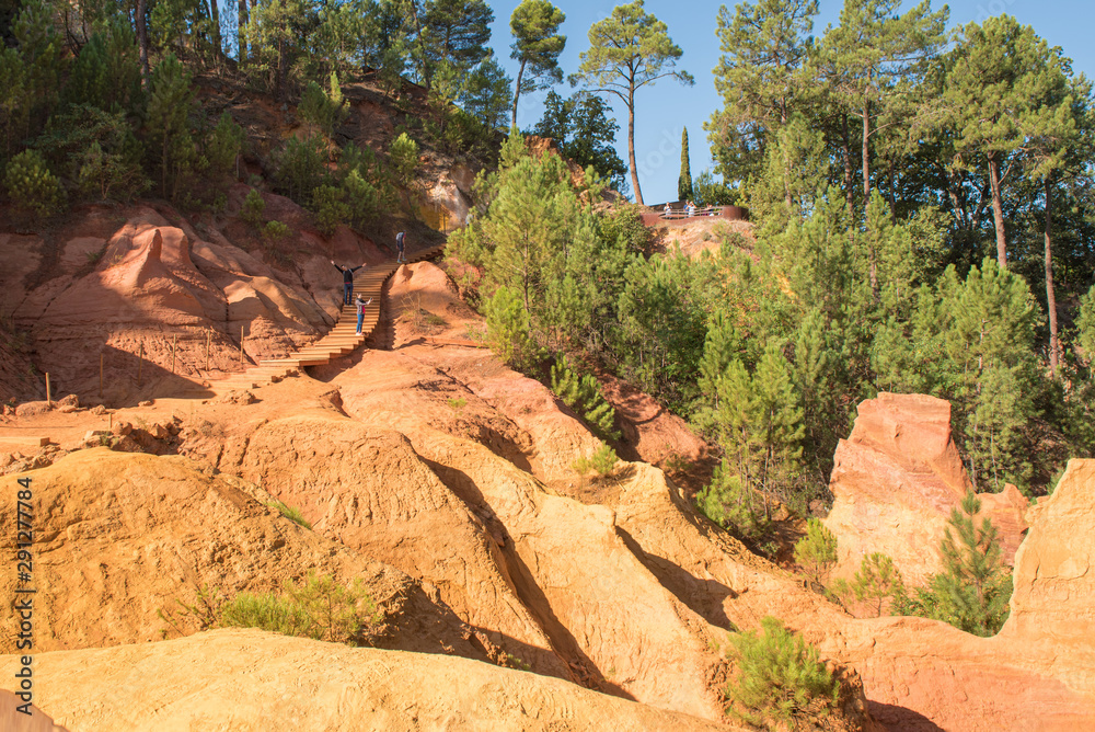 Ochre Trail in Roussillon, Sentier des Ocres, hiking path in a natural colorful area of red and yellow cliffs surrounded by green forest in Provence