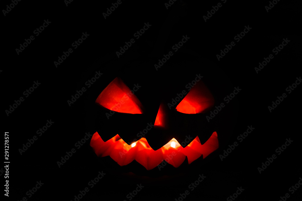 Carved halloween pumpkin jack-o-lantern glows in a darkness Carved halloween pumpkin jack-o-lantern glows in a darkness
