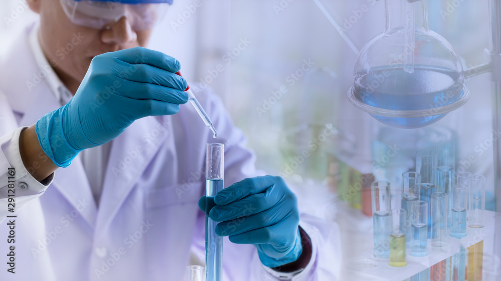 Fototapeta premium Laboratory research concept; scientist dropping chemical reagent into test tube with lab glassware background. Research in chemical laboratory.