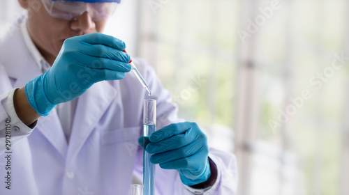Laboratory research concept; scientist dropping chemical reagent into test tube. Research in chemical laboratory.