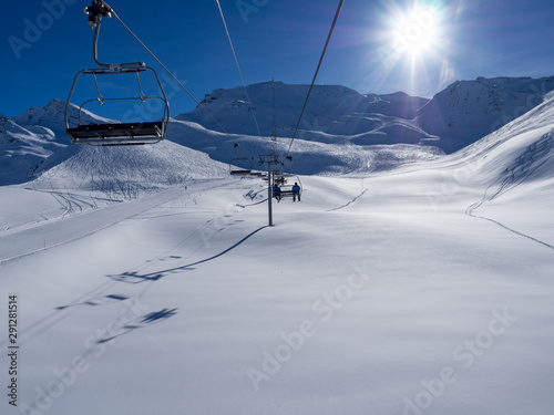 France, february 2019: Panoramic view of a snow covered alpine mountain range with chairlift ski lift in sun. Alpes