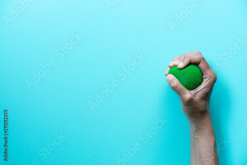 Hands of a woman squeezing a stress ball on green background