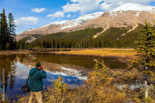 Man tourist in green jacket photographs