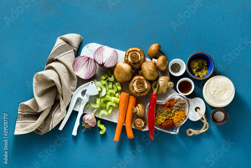 Ingredients for cooking Indian curry from vegetables, pumpkins and mushrooms on a blue background and spices. shot from above. copy space