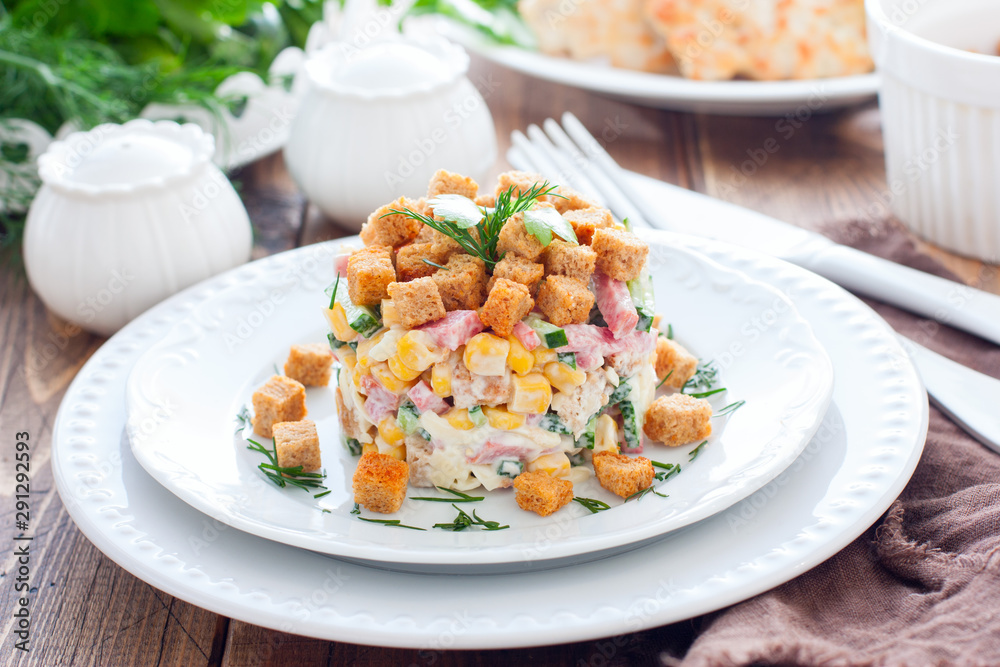 Salad with smoked sausage and crackers on a white plate in a portion serving, horizontal Salad with smoked sausage and crackers on a white plate in a portion serving, horizontal