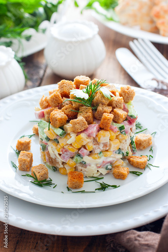 Salad with smoked sausage and crackers on a white plate in a portion serving, selective focus
