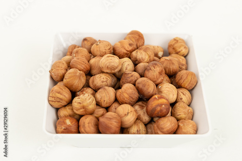 peeled hazelnuts in a white bowl on a white background