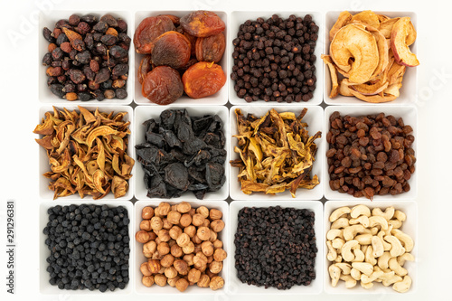 Groups of various kinds of dried fruits in square white bowls on white background