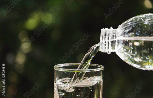 Pouring water from bottle into the glass on blurred background.