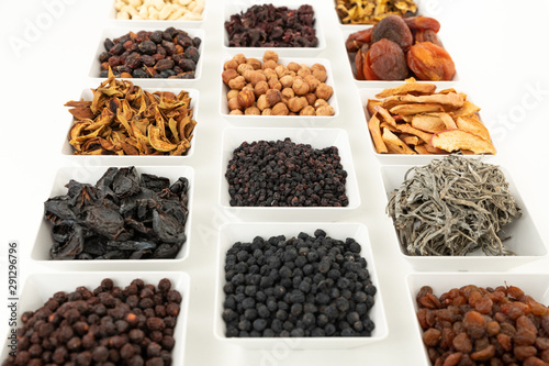 Groups of various kinds of dried fruits in square white bowls on white background