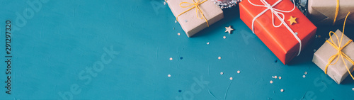 Winter holidays. Cropped flat lay of beige and red gift boxes, star and round shape glitter on teal blue background. Copy space. photo