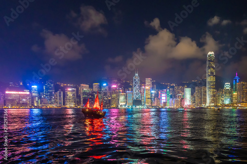 The Aqua Luna sailing in Hong Kong Downtown with skyscraper buildings. financial district in urban city at night. The red boat or ship is a Chinese Junk operating in Victoria Harbour. photo