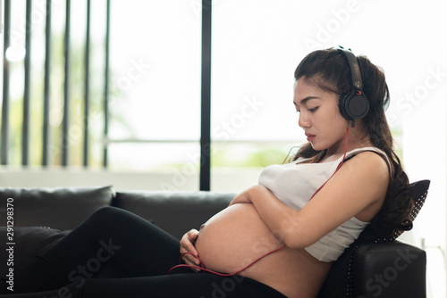 pregnanting woman sitting at sofa and lisening music photo