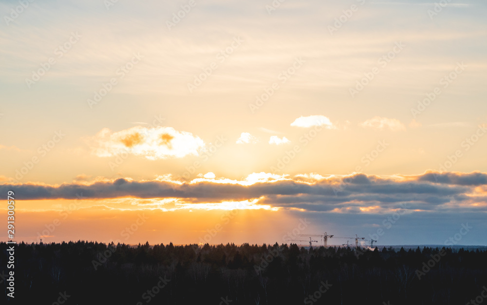 Sunset over forest with silhouettes of construction cranes. Construction of new apartment building. Krasnogorsk, Russia. Sunset over forest with silhouettes of construction cranes. Construction of new apartment building. Krasnogorsk, Russia.