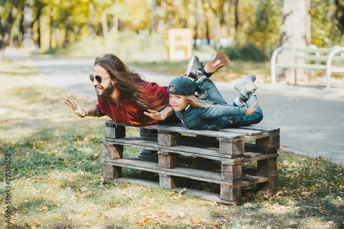 Father and little son doing yoga exercises together in autumn park. photo