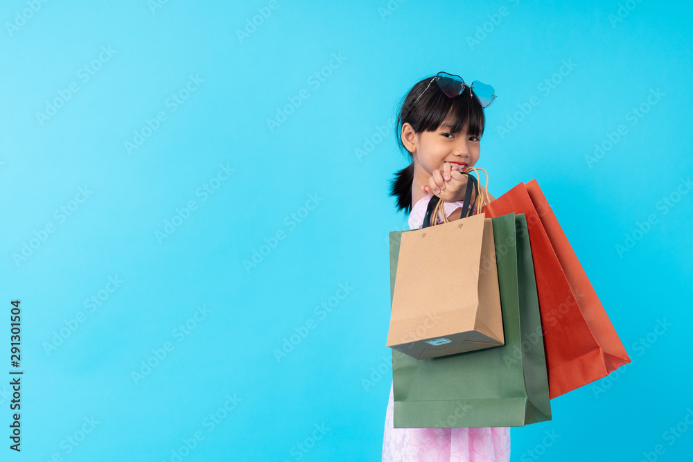 happy young Asian girl kid stylish holding shopping bag on blue background in studio, lifestyle of paid for kids fashion style concept happy young Asian girl kid stylish holding shopping bag on blue background in studio, lifestyle of paid for kids fashion style concept