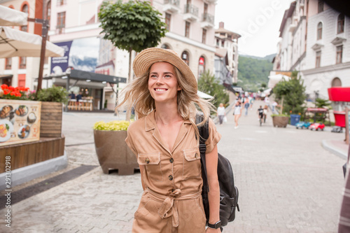 Happy young caucasian woman stylish traveler with hat walks around european city. Charming young female student enjoying European country vacation. Travel new impressions concept