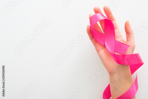 Female hand with pink ribbon as a symbol of the fight against breast cancer over white background. Breast cancer awareness month concept.