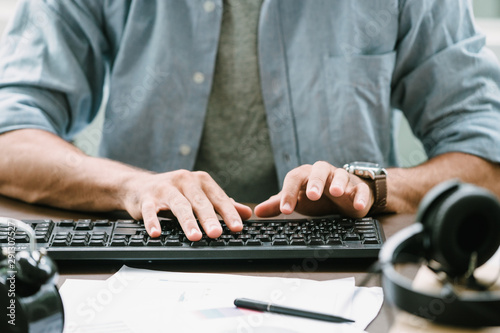 working man in casual shirt typing at computer keyboard