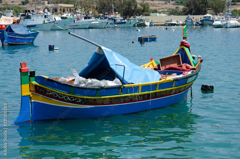 Malta - Colorful traditional Luzzu fishing boat at Marsaxlokk on a sunny summer day with green sea and blue sky