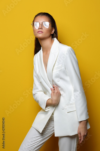 Elegant young woman in glasses on a yellow background