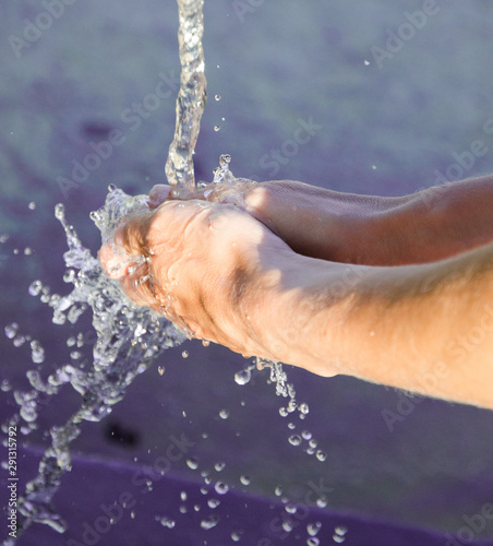 Female hand. Woman washes her hands under flowing water in a city fountain at the sports ground. Clear water is available everywhere in Spain. Clean hands and fresh skin.