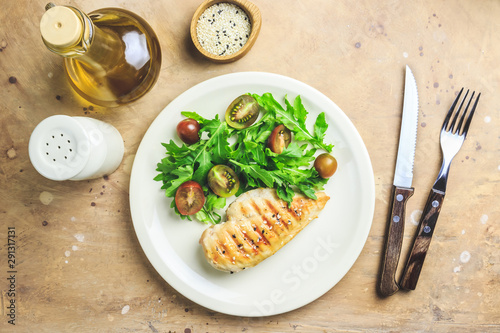 Chicken fillet salad with tomato and arugula leaves.