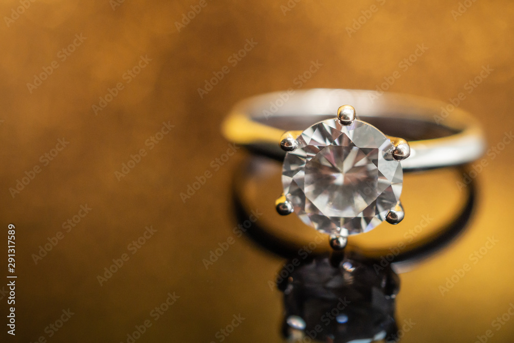 Jewelry wedding diamond ring on golden background with reflection