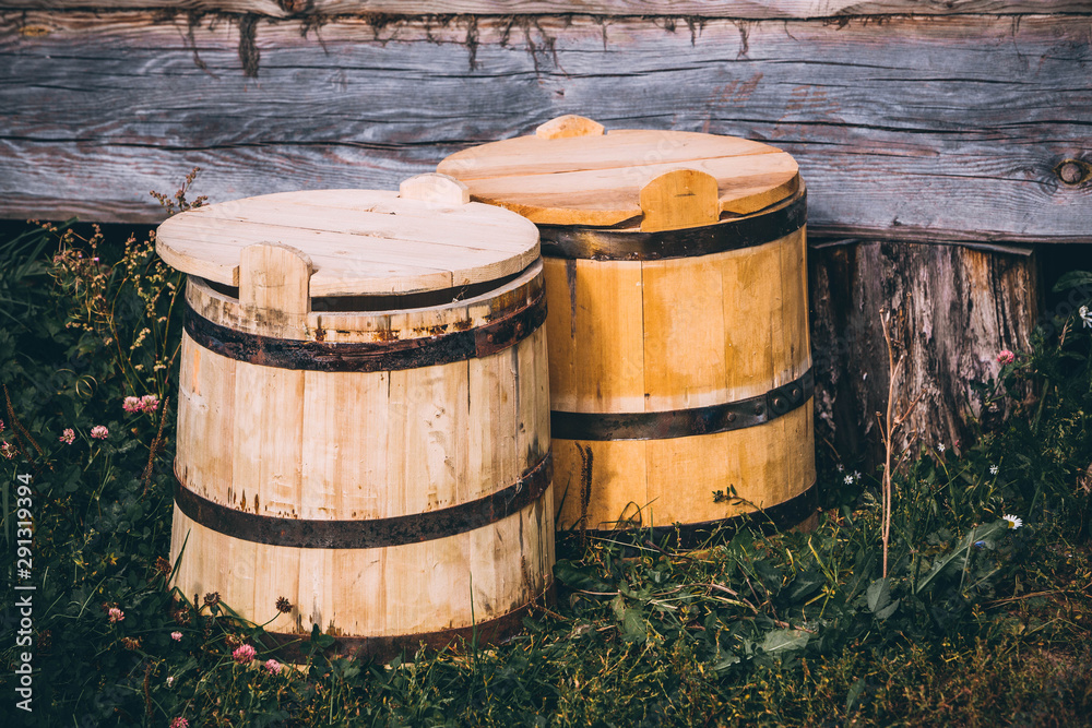 Fototapeta premium wooden barrels next to a wooden log house