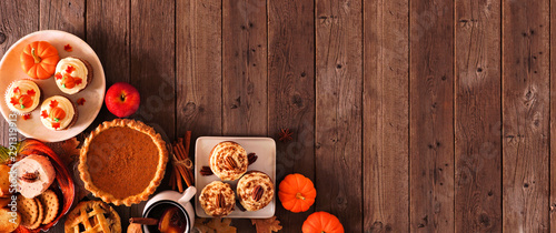Autumn food corner border banner. Table scene with a selection of pies, appetizers and desserts. Top view over a rustic wood background. Copy space.