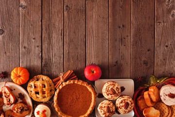 Autumn food bottom border. Table scene with a selection of pies, appetizers and desserts. Top view over a rustic wood background. Copy space.
