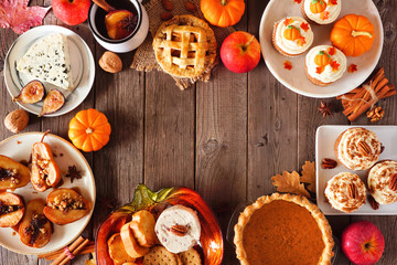 Autumn food frame. Table scene with a selection of pies, appetizers and desserts. Top view over a rustic wood background. Copy space.