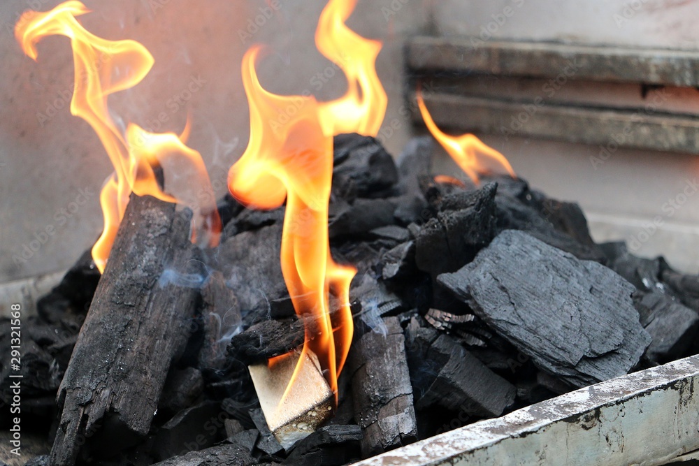 close up of flames between the charcoals in the barbecue grill close up of flames between the charcoals in the barbecue grill