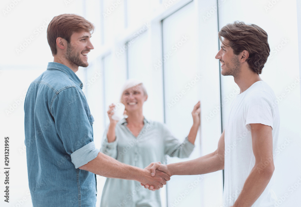 colleagues shaking hands in the office lobby colleagues shaking hands in the office lobby