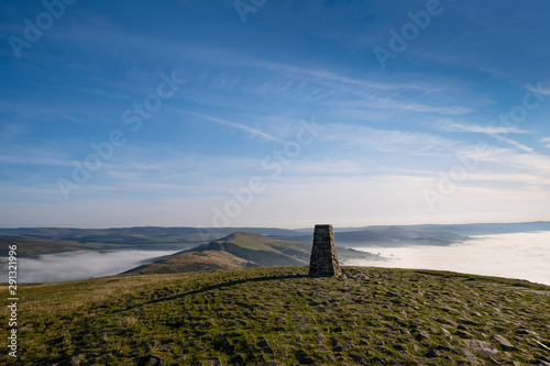Trig point on top of Mam Tor, Peak District, UK. Early morning with mist in Edale and Hope Valley, and the Great Ridge rising above the mist photo