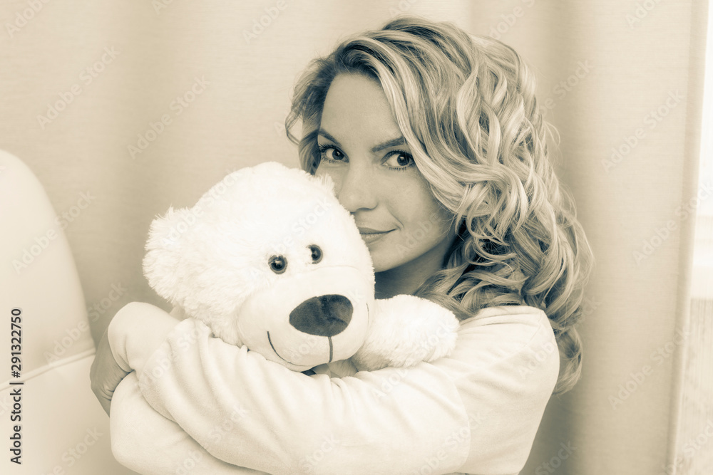Portrait of a beautiful, sexy, sweet, gentle girl with a white cozy Bear at home in pajamas.