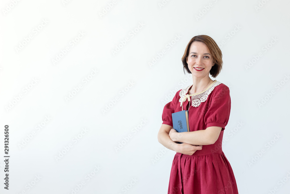 Portrait of cute smiling modest woman in dress holding classic book in hands on white background. Concept of lovers of history and classics. Copy space Portrait of cute smiling modest woman in dress holding classic book in hands on white background. Concept of lovers of history and classics. Copy space
