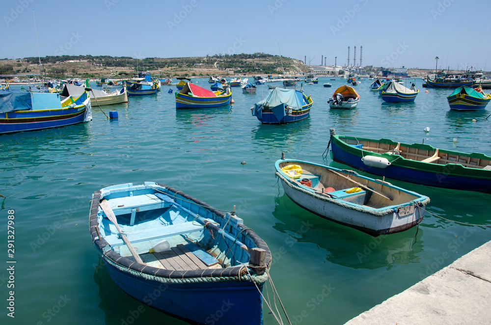 Colorful traditional Luzzu fishing boat at Marsaxlokk on a sunny summer day with green sea and blue sky