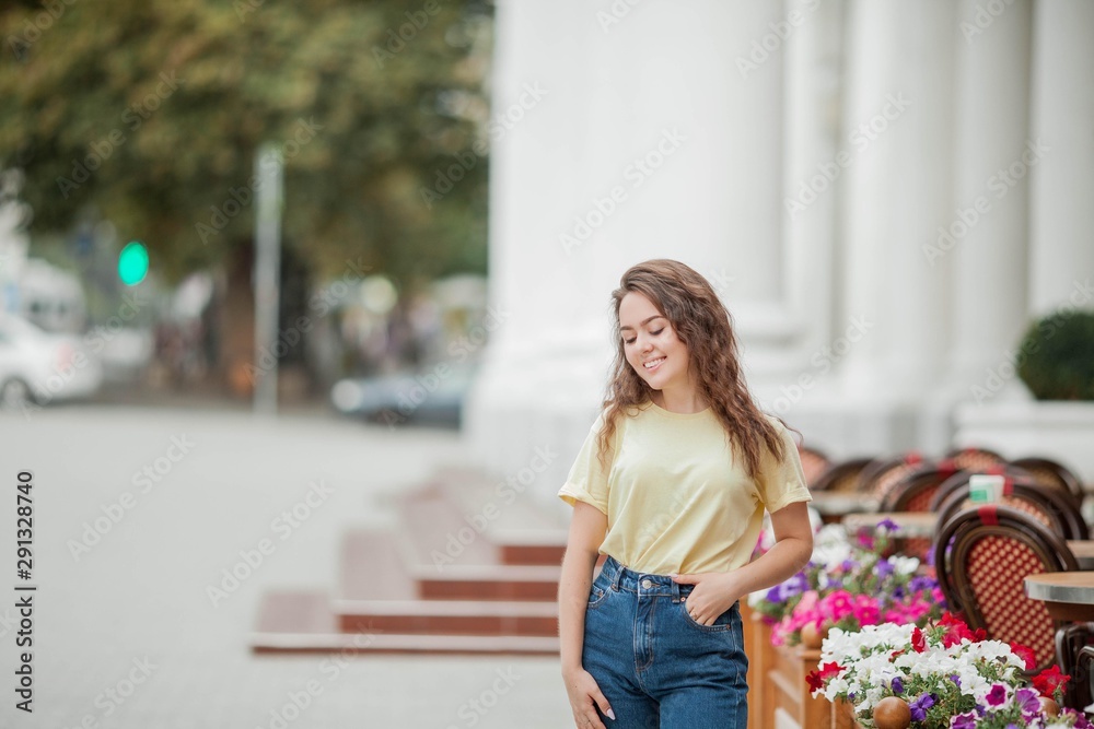 A beautiful young woman of 16 years old stands near a French cafe. Tourism. flowers. Summer.