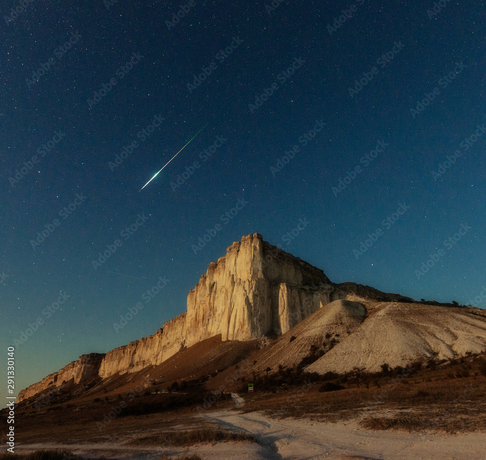 Obraz premium Night star sky and meteor over rock