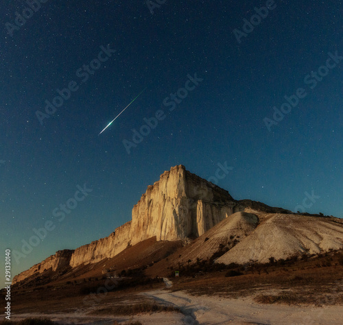 Night star sky and meteor over rock