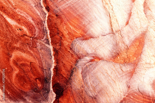 Jordan: rock face of Petra, with streaks that form red, white and yellow waves. Warm light, background, wallpaper.