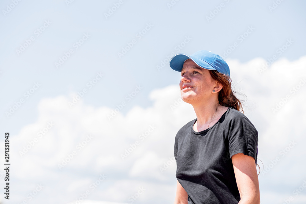 Young caucasian woman in summer clothes looking away on blue sky background Young caucasian woman in summer clothes looking away on blue sky background