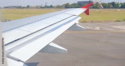 Airplane getting in front of a line of planes for takeoff on airport runway - view of the wing. photo