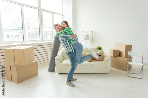 Young couple in denim pants embracing rejoicing in their new apartment during the move. The concept of housewarming and credit for new housing.