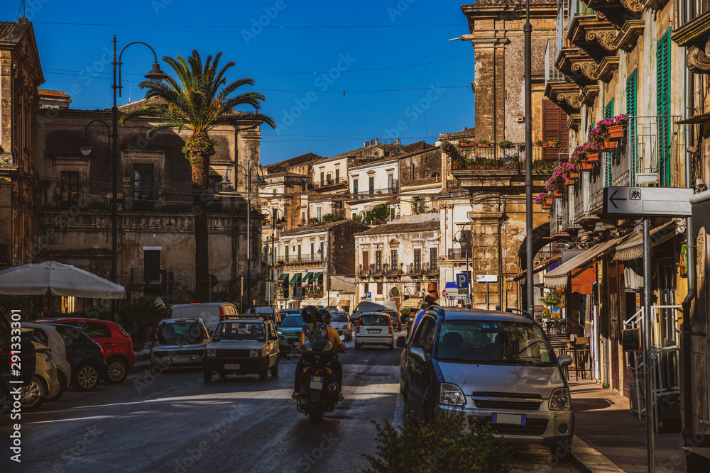 Old town street with typical italian traffic in famous baroque sicilian town Modica in Sicily, south Italy