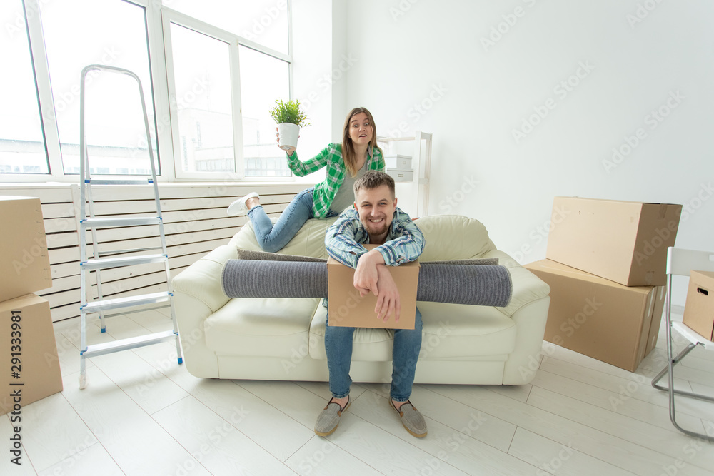 Cheerful young couple rejoices in moving to a new home laying out their belongings in the living room. Concept of housewarming and mortgages for a young family