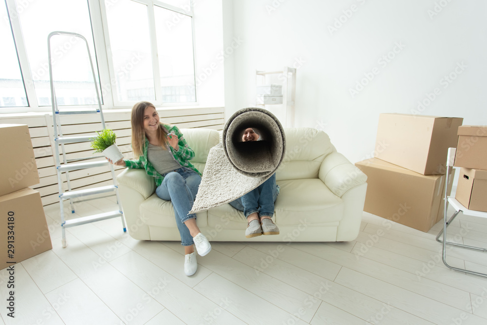 Funny young couple charming girl and handsome man holding a box with things and a pot with a plant while moving to a new apartment. Housewarming and mortgage concept. Funny young couple charming girl and handsome man holding a box with things and a pot with a plant while moving to a new apartment. Housewarming and mortgage concept.