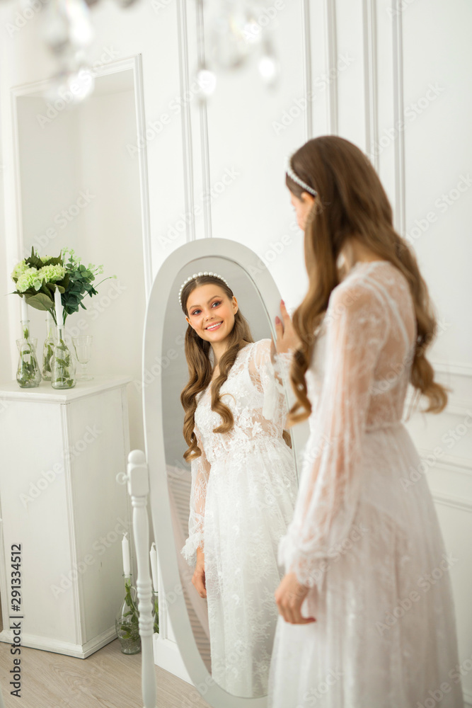 beautiful young woman with makeup and hairstyle in a delicate peignoir near the mirror beautiful young woman with makeup and hairstyle in a delicate peignoir near the mirror