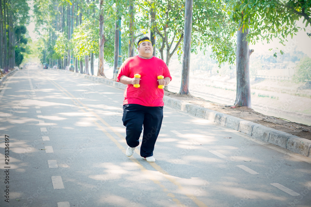 Overweight man jogging with dumbbells in the park Overweight man jogging with dumbbells in the park